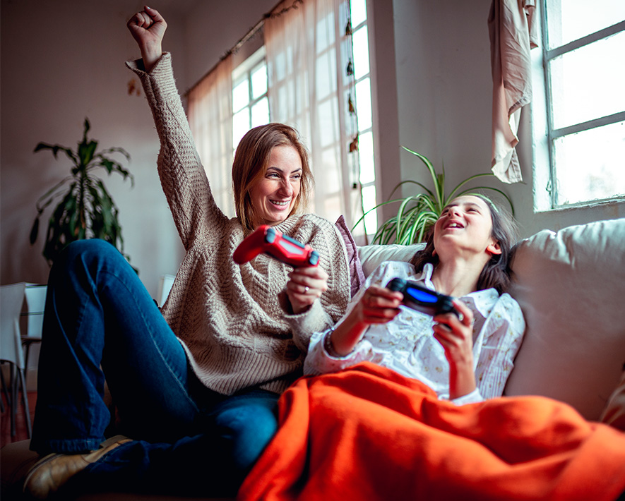 Madre e Hija jugando con consola en sofa