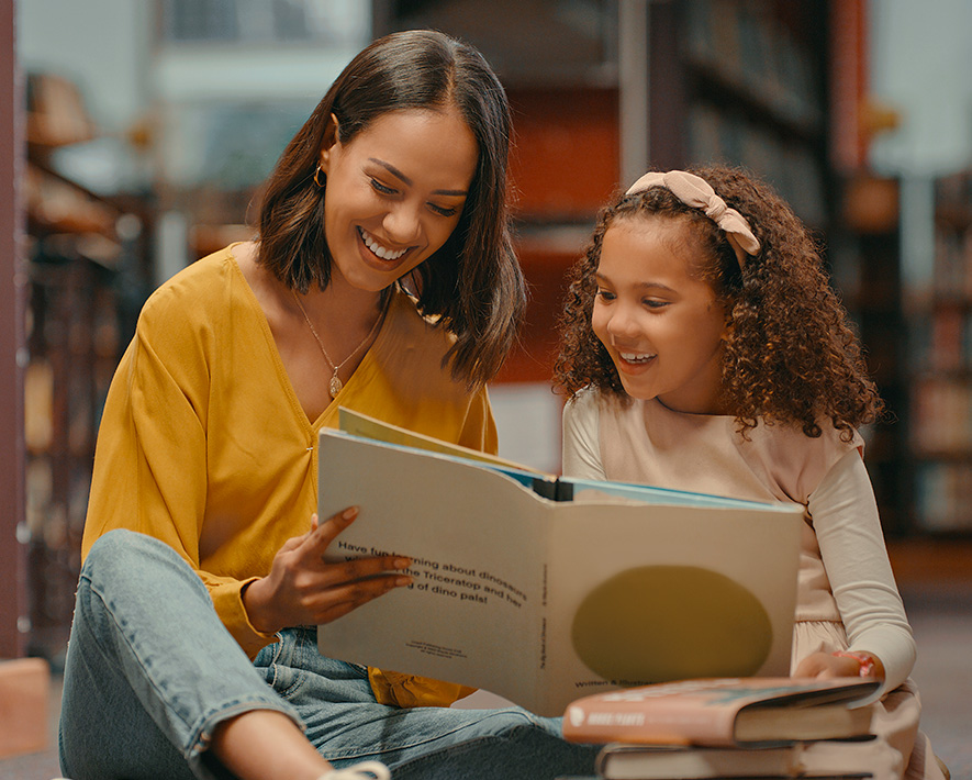 Persona adulta leyendole libro a niña